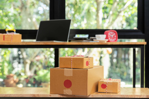 Картонная коробка и ноутбук на столе на рабочем месте стартапа владельца малого бизнеса для онлайн-продажи. - Фото, изображение