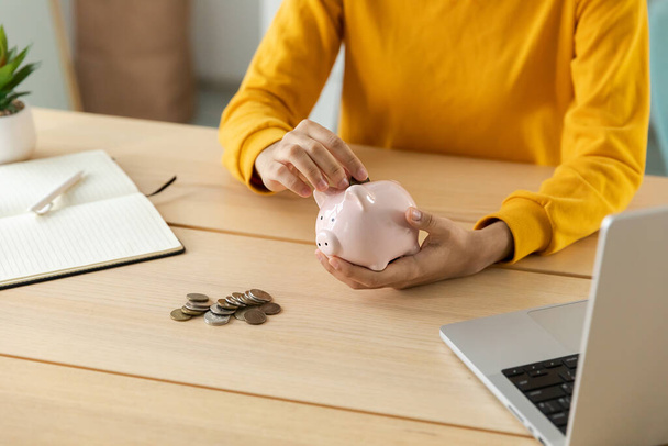Saving money investment for future. Female woman hands holding pink piggy bank and putting money coin. Saving investment budget business wealth retirement financial money banking concept - Фото, зображення