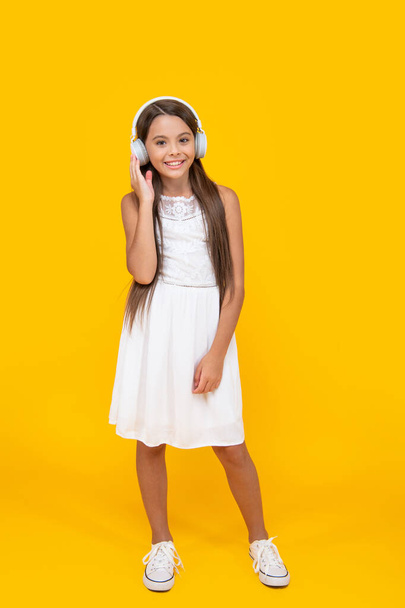 teen girl smile listen music in headphones on yellow background. - Zdjęcie, obraz