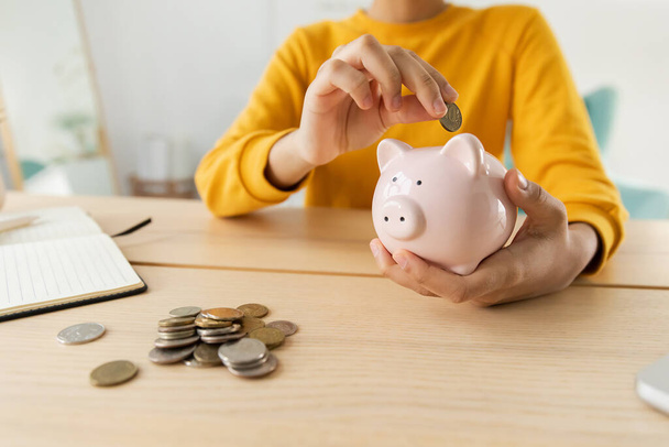 Saving money investment for future. African american girl holding pink piggy bank and putting money coin. Saving investment budget business wealth retirement financial money banking concept - Photo, Image