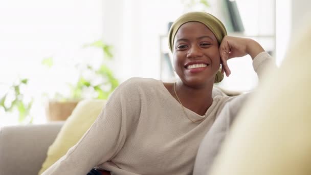 Canapé femme noire bonheur, visage et salon avec une personne africaine assise avec un sourire relaxant. Salon à la maison, portrait heureux et féminin dans un foyer se sentant calme le matin prêt à commencer la journée. - Séquence, vidéo