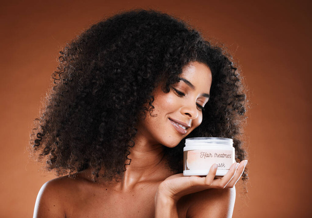 Beauty, haircare and product with a model black woman in studio on a brown background for treatment. Container, hair mask and wellness with an attractive young female posing to promote cosmetics. - Foto, Imagem