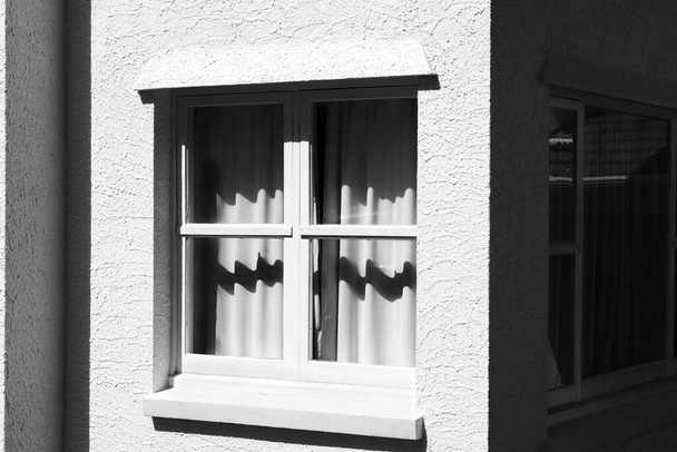 Stucco εξωτερικό και ξύλινο πλαισιωμένο σκιές παραθύρων σε λευκές κουρτίνες - Φωτογραφία, εικόνα