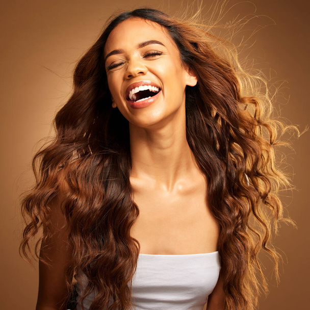 Freedom, hair and excitement with a model woman on a brown background in studio for natural haircare. Happy, salon and shampoo with an attractive young female feeling excited by keratin treatment. - Photo, image