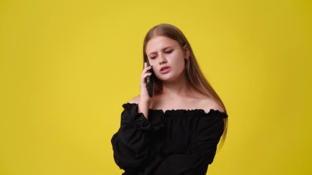 4k video yksi tyttö puhuu puhelimessa negatiivinen ilme keltaisella taustalla. Käsite - Materiaali, video