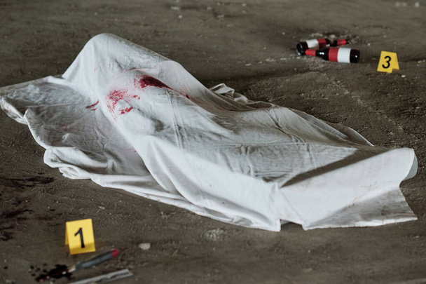 Weißes Laken mit Blutflecken bedeckt Leiche mit Handfeuerwaffe erschossen oder mit Messer oder einer anderen Mordwaffe getötet - Foto, Bild
