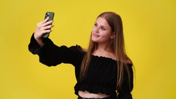 4k video yksi tyttö, joka ottaa selfiet hänen puhelimeen ja näyttää rauhan merkki keltaisella taustalla. Tunteiden käsite. - Materiaali, video