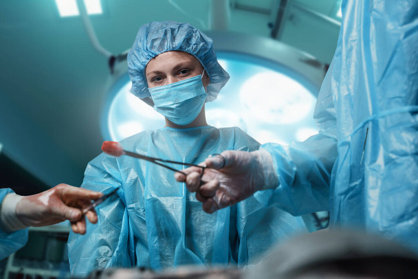 Shot of professional doctor woman looking at camera during operation. - 写真・画像