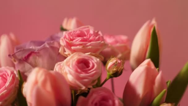 Zbliżenie pionowy plan letniego różowego bukietu kwiatów. Tulipany i róże na neonowym tle z przestrzenią do kopiowania, wklej tekst - Materiał filmowy, wideo