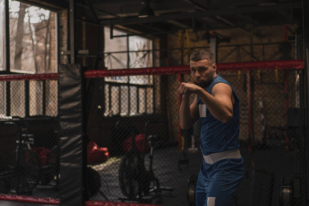 Un boxeur dans la salle de gym qui se bat avec des coups de poing d'exercices d'ombre - Photo, image
