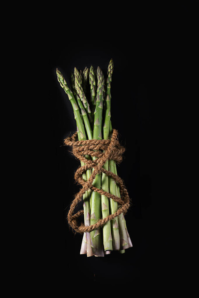 Asparagus on blue dish on black background with cocos rope - Photo, image