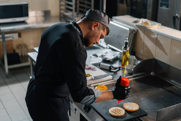 професійна кухня в готельному ресторані шеф-кухар мазає соусом на булочках для бургеру
 - Фото, зображення