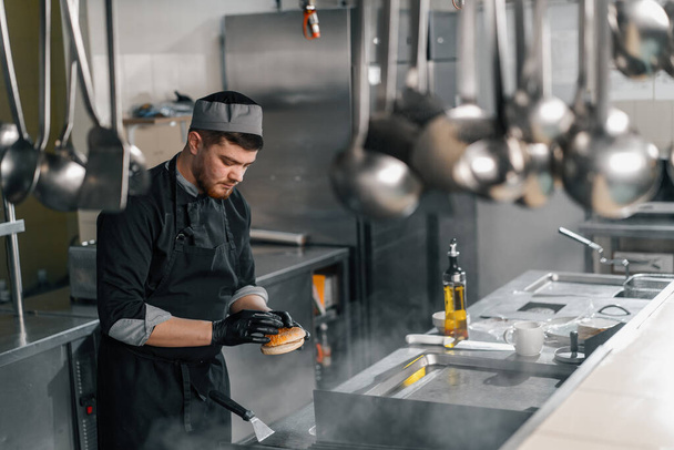 Profi-Küche im Hotelrestaurant Koch legt Burger-Brötchen auf den Grill - Foto, Bild