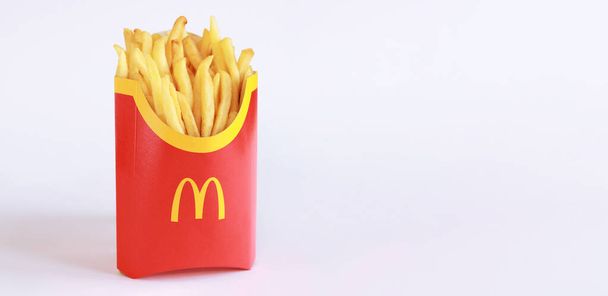 Kyiv, Ukraine - March 22, 2023: McDonald French Fries in paper cup or package isolated on white background. McDonald's Corporation is the world's largest fast food restaurant. French fries on a light background with empty space for text - Fotó, kép