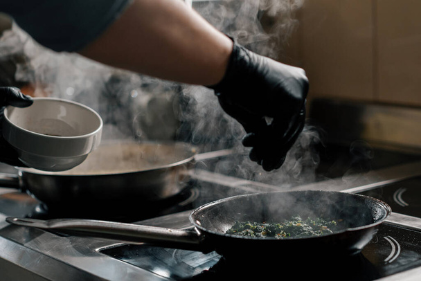 Szakmai konyha a szálloda éttermében közelkép a séf készít spenót serpenyőben - Fotó, kép