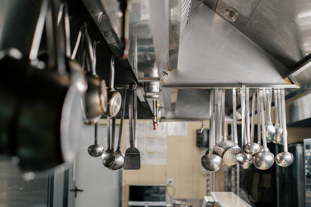 professional kitchen in the hotel restaurant dishes ladles hang on hood - Photo, Image