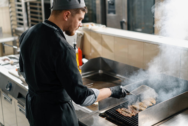 professionelle Küche im Hotelrestaurant der Koch bereitet Hühnchen für Club-Sandwich auf dem Grill zu - Foto, Bild