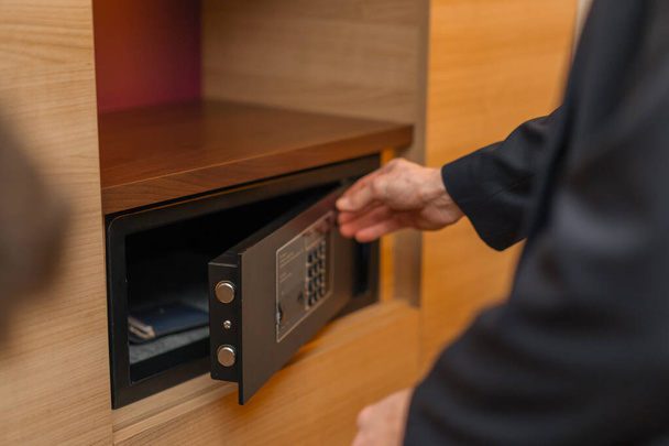 Рука вводит код, чтобы открыть и запереть сейф или сейф в гостиничном номере - Фото, изображение
