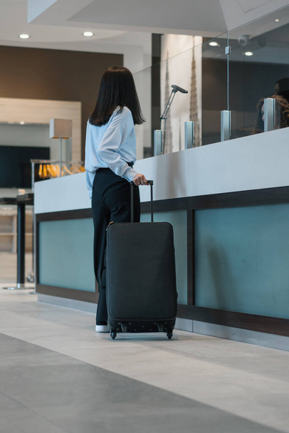 Giovane donna d'affari arrivata in hotel con una valigia concetto di viaggio - Foto, immagini