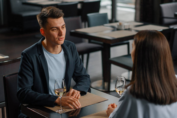 Un appuntamento in un hotel ristorante uomo e una donna bere vino bianco in bicchieri primo piano - Foto, immagini