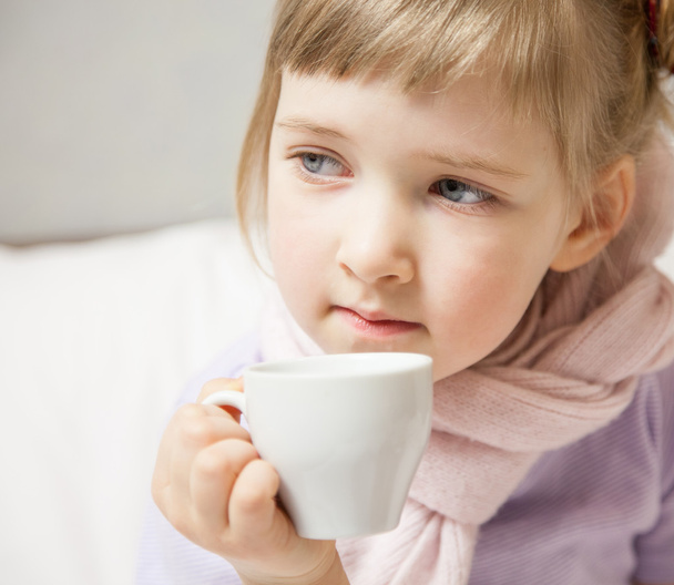 Little girl sitting in a bed with cup - Фото, изображение