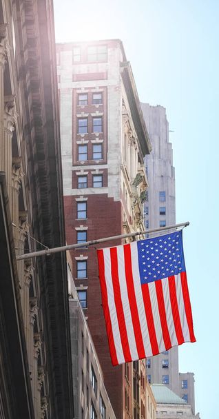 American flag with buildings in background, selective focus, New York City, USA. - 写真・画像