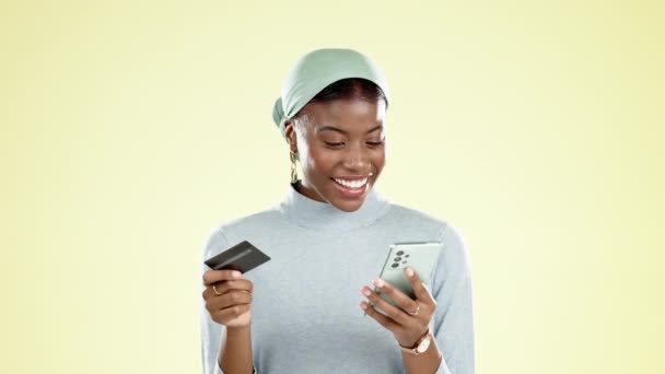 Мобильный телефон, кредитная карта и черная женщина в студии делает онлайн покупки для продажи или скидки. Счастливые, улыбка и африканская женщина покупка с сайта электронной коммерции розничной торговли с телефоном на желтом фоне - Кадры, видео