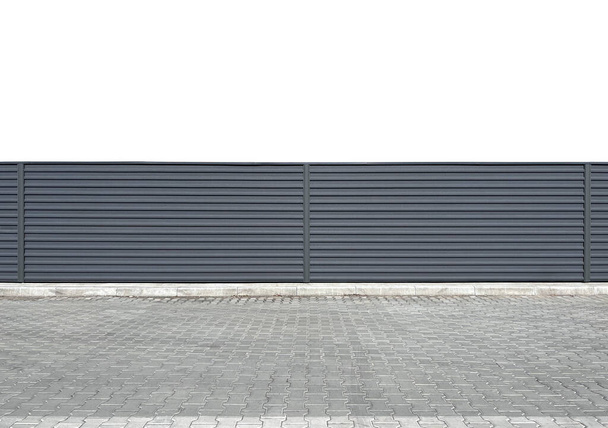 Городской стальной гофрированный забор, расположенный на белом фоне вдоль дороги. Серый современный забор или изгородь. Городская среда. Шаблон или макет - Фото, изображение