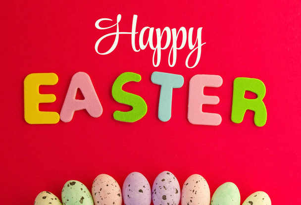 Happy Easter text with red background decorated with chocolate eggs. Can be used to say Happy Easter to anyone. - 写真・画像