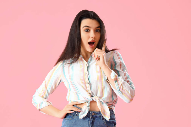 Surprised young woman in shirt on pink background - Foto, Imagem