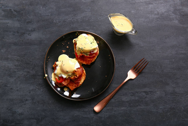 Plate with delicious eggs Benedict on black grunge table - Photo, Image