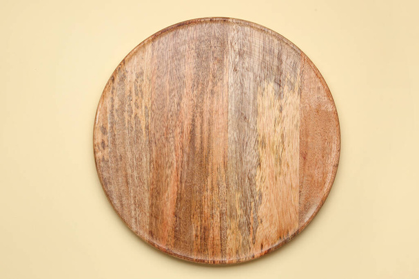 Round wooden board on yellow background - Фото, изображение