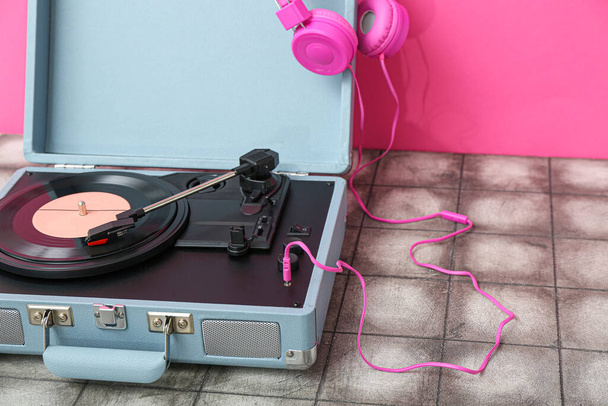 Gravador com disco de vinil e fones de ouvido na mesa perto da parede rosa, close-up - Foto, Imagem