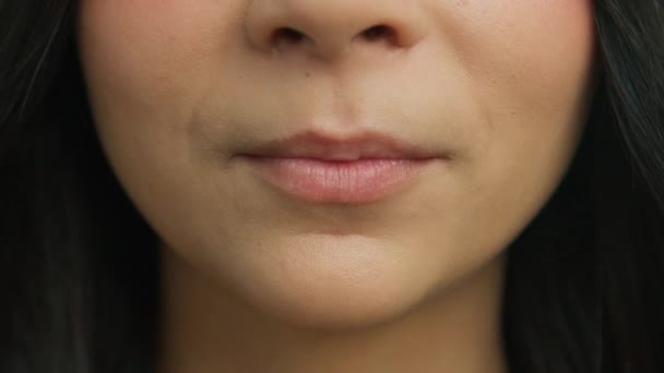 Close-up van sensuele vrouw bijten en likken mollige lippen in slow motion. Jonge vrouw gezicht bijten sexy lippen en likken met tong. Aantrekkelijke jonge meisjes lippen en mond, gezonde witte tanden, huid gezicht - Video