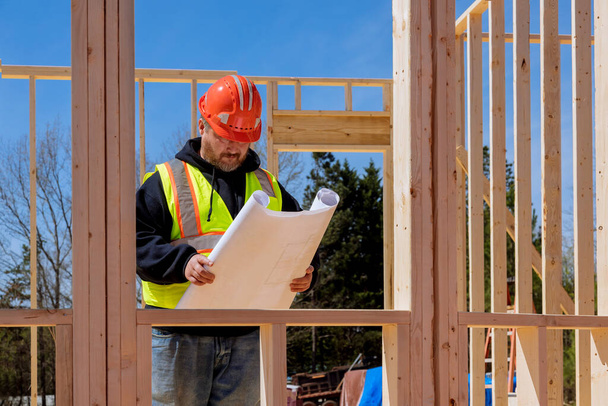 En el sitio de construcción, un inspector verifica la construcción de la casa según el plan de construcción - Foto, imagen