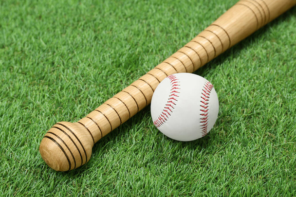 Wooden baseball bat and ball on green grass. Sports equipment - Fotoğraf, Görsel