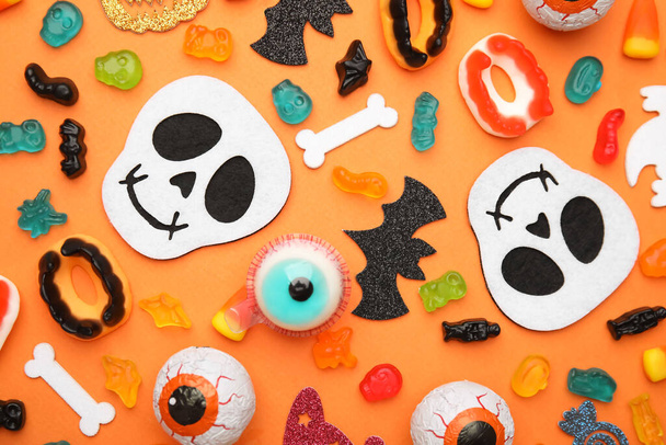 Tasty candies and Halloween decorations on orange background, flat lay - Фото, изображение