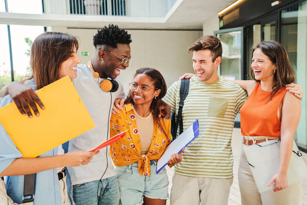 Group of multiracial students talking and smiling after class at university campus. Diverse tenagers laughing and having fun at the breack of the high school. Education concept. High quality photo - Photo, Image