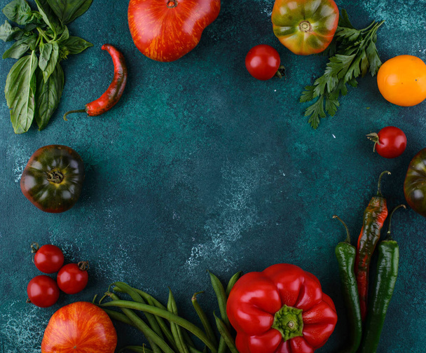 Ассортимент помидоров различного сорта, перца и базилика на зеленом фоне - Фото, изображение