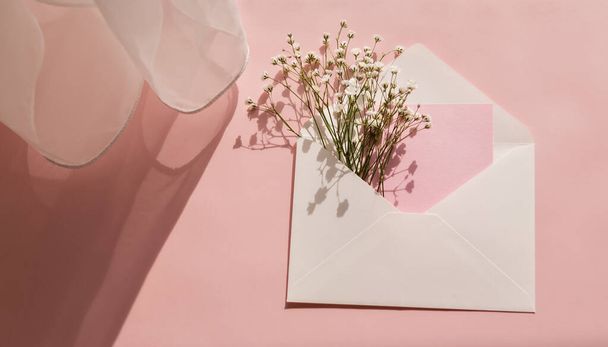 White gypsophila in a white envelope on pink background. Congratulation card, Womens Day, Mothers Day, Valentines, birthday.Mockup. - Fotografie, Obrázek