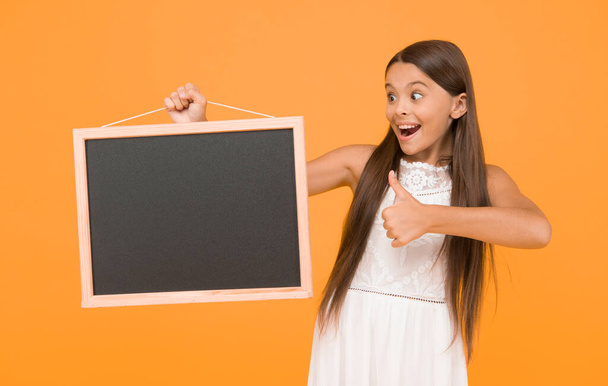 Small kid with blank blackboard. Advertisement promotion copy space. Good news for you. Chalkboard for information. Blank blackboard. Something you need to know. Happy smiling girl hold blackboard. - Foto, afbeelding
