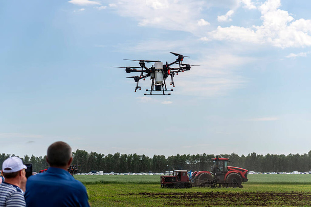 agricultural drone spray a field. farmers watch and control remotely a drone for processing fields. - Photo, Image