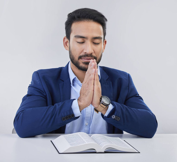 Mockup, faith and Asian man, praying, bible and guidance against grey studio background. Japanese male, believer and Christian guy with holy book, prayer and hope for solution, religious or gratitude. - Fotografie, Obrázek