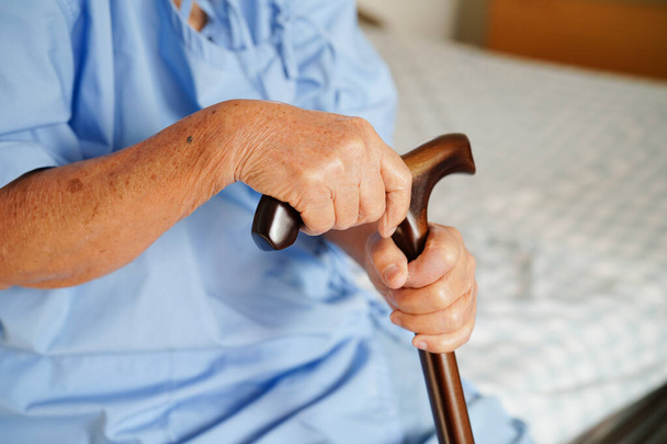 Asian elderly disability woman patient holding walking stick in wrinkled hand at hospital.  - Zdjęcie, obraz