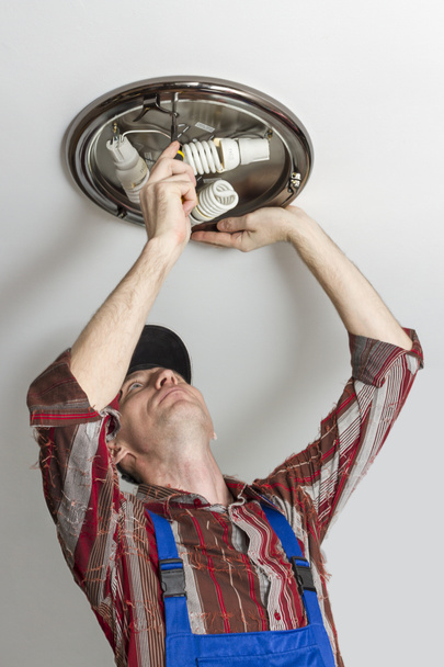 Electricista instala la iluminación de la lámpara en el techo de la habitación
. - Foto, imagen