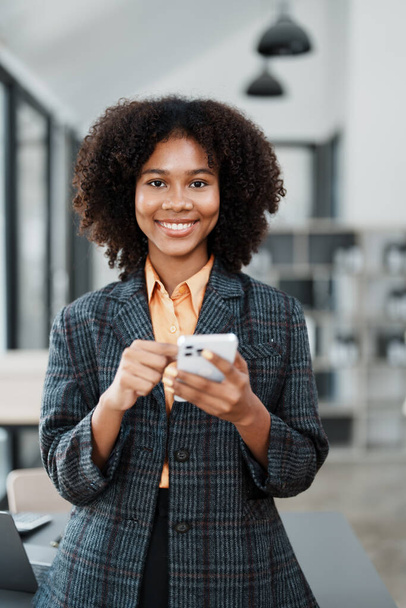 Hermosa joven adolescente estadounidense africano que trabaja en el teléfono inteligente móvil con en documento do, impuestos, intercambio, contabilidad y asesor financiero. - Foto, imagen