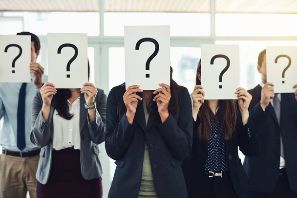 Ideje feltenni a nehéz kérdéseket. egy csoport üzletember, akik kérdőjeleket tartanak az arcuk előtt. - Fotó, kép