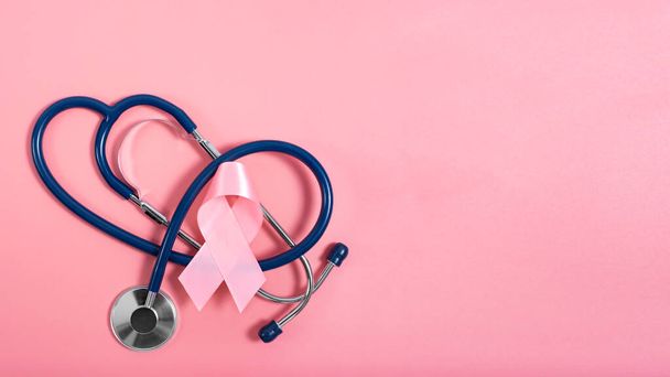 Stethoscope and pink ribbon on pink background as breast cancer awareness symbols. Flat lay view - Fotó, kép