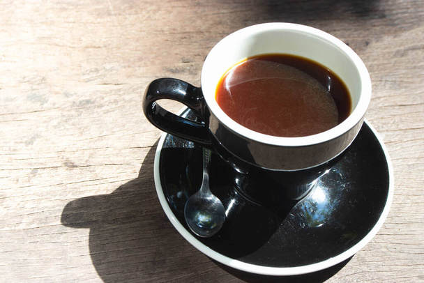 Draufsicht auf heißen Amerucano-Kaffee in schwarzer Keramiktasse auf Holzhintergrund. - Foto, Bild