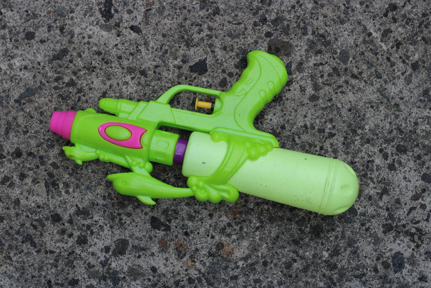 Foto da arma de brinquedo verde no chão - Foto, Imagem